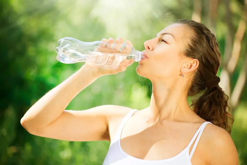 Woman drinking water in sun – stay hydrated while tanning outdoors